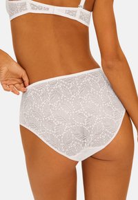 Witte kantenslips met een gestructureerd bladdessin, een gladde tailleband en een hoog uitgesneden beenontwerp, die een delicaat en ademend uiterlijk bieden.