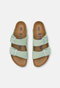 Green leather sandals with two adjustable silver buckles, cork insole, and a flat design. Size marked as 38. Smooth texture and open toe.