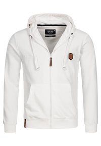 Hvid hættetrøje med lynlås lavet af blødt stof, med hætte, forlommer og en brun accenteret lap på venstre bryst og kant.