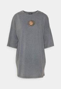 Šedé oversized tričko vyrobené z měkké látky, s centrálním vyšívaným motivem slunce a měsíce v zemských tónech. Krátké rukávy.