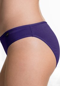 Mutandine hipster in cotone viola con una texture liscia. Presenta un design a vita bassa e un piccolo dettaglio floreale sul cinturino.