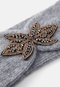 Fascia per capelli in maglia grigia con un design a foglia perline in tonalità bronzo e nero, caratterizzata da trame intricate e una finitura in tessuto morbido.