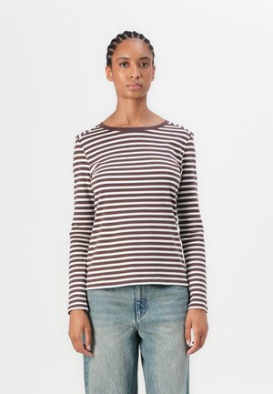 Chemise à manches longues rayée marron et crème avec un col rond et des boutons sur les épaules, assortie à un jean en denim bleu clair.