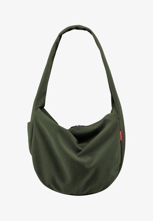 Sac d'épaule en tissu côtelé vert olive avec une large bandoulière et une petite étiquette rouge sur le côté, doté d'une fermeture éclair en haut.