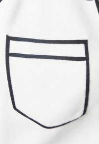 Vit tyg med en liten, skissad fickdesign i svart tråd. Har en enkel, ren form och slät textur.