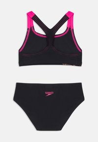 O conjunto de fato de banho preto inclui um top com costas nadador com detalhes e costura em rosa, e uma parte de baixo correspondente, apresentando um pequeno logótipo impresso.