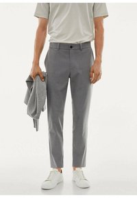 Szare, dopasowane spodnie wykonane z lekkiego materiału, charakteryzujące się eleganckim designem, przednimi kieszeniami, zapięciem na guziki, noszone z białymi trampkami.