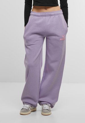 Helllila Sweatpants mit elastischem Bund, seitlichen Taschen und einem kleinen pinken Logo-Detail. Das Material wirkt weich und hat eine lockere Passform.