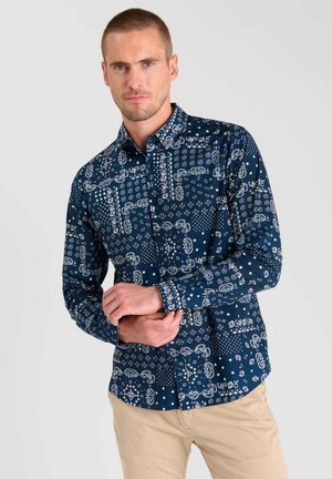 Chemise marine avec des motifs géométriques et paisley blancs, manches longues, col boutonné et coupe ajustée. Tissu en coton doux.