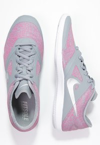 Scarpe da ginnastica grigio chiaro con accenti texturizzati rosa, tomaia in tessuto, chiusura con lacci e suola in gomma bianca. Presenta un logo argentato sul lato.
