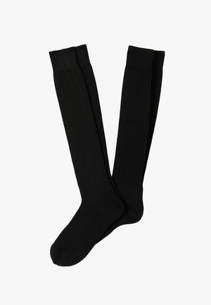 Ein Paar schwarze, knielange, gerippte Socken flach gegen einen weißen Hintergrund gelegt.