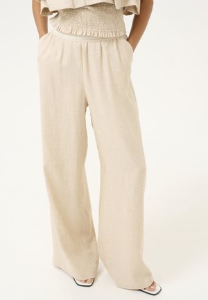 Beige wide-leg pants made of textured fabric, featuring a relaxed fit and side pockets. Waistband is smooth and elastic for comfort.