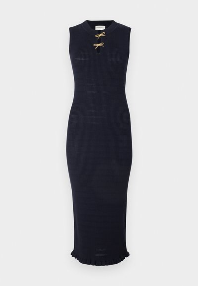 Robe midi tricotée de couleur bleu marine, sans manches, avec un décolleté rond et un accent décoratif en forme de nœud doré à l'avant. Ourlet froncé.