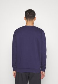 Felpa blu navy con scollo rotondo, maniche lunghe e orlo a costine. Il materiale sembra morbido con una texture liscia. Nessun motivo visibile.