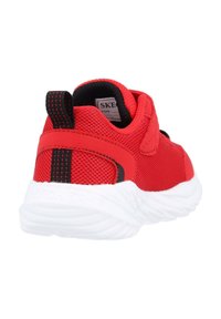 Zapatilla deportiva roja con parte superior de malla, correa ajustable y suela de goma blanca. Presenta una franja negra en el talón para un detalle adicional.