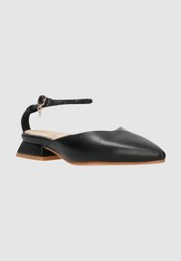 Pompa slingback in pelle nera con punta affusolata e tacco basso a blocco. Caratterizzata da una sottile cinghia alla caviglia con dettaglio fibbia.
