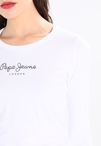 Weißes Langarmshirt aus Baumwolle mit rundem Ausschnitt und einem aufgedruckten "Pepe Jeans London"-Logo in Dunkelgrau.