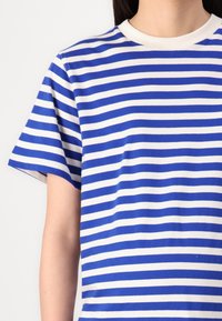 Camiseta de manga corta a rayas azules y blancas con cuello redondo, hecha de una tela suave, que presenta rayas horizontales espaciadas uniformemente.