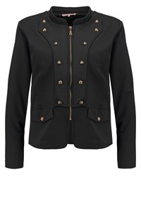 Czarna kurtka z zamkiem z przodu, ozdobiona złotymi ćwiekami w okolicy klatki piersiowej oraz dwoma przednimi kieszeniami z podobnymi akcentami. Gładka tekstura materiału.