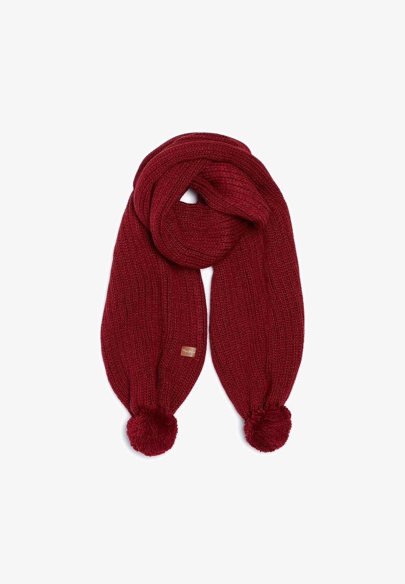 Écharpe rouge tricotée avec une texture côtelée épaisse, des pompons à chaque extrémité et une petite étiquette de marque rectangulaire.