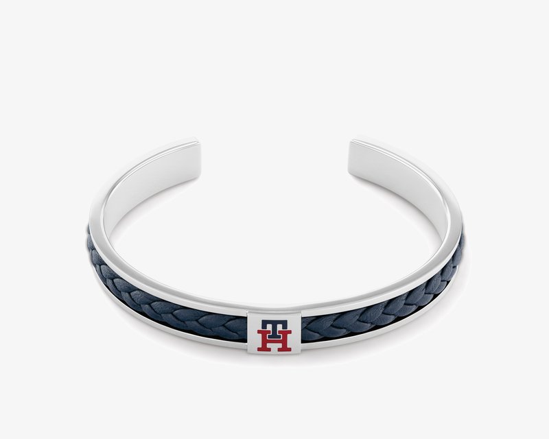 Silver cuff bracelet featuring a dark blue braided leather band with a rectangular metal accent displaying red and blue lettering.
