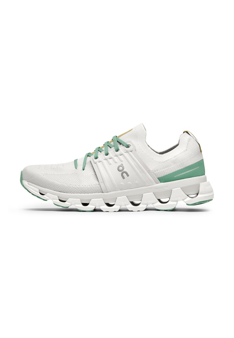 Baskets blanches avec des accents vert menthe, tige en tricot texturé et une semelle distinctive rembourrée, dotée de segments creux et segmentés.
