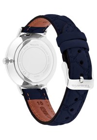 Zilveren roestvrijstalen horloge met een marineblauwe leren band en bruine leren voering, met een gladde, ronde achterkant en metalen sluiting.