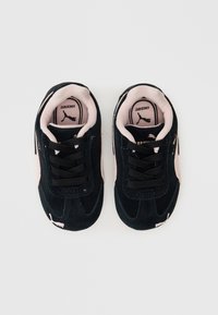 Černé semišové tenisky s růžovými akcenty, s tkaničkami, zaoblenou špičkou a logem na jazyku. Vhodné pro volnočasové nošení.