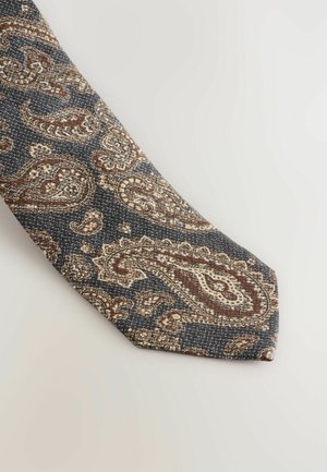 Marineblauwe stropdas met een paisleypatroon in bruin, crème en goudtinten. Geweven stof met een puntige punt, die ingewikkelde details toont.