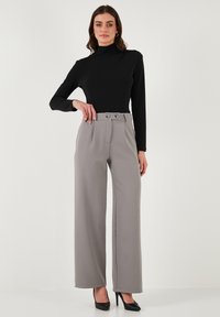 Black long-sleeve top paired with high-waisted, wide-leg gray trousers featuring a front belt, double buttons, and smooth fabric texture.