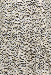 Mönstrad tyg i gult, blått och svart med en strukturerad yta och gathered-detalj vid fållen, vilket skapar ett flödande utseende.