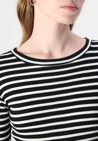 Schwarz-weiß gestreiftes, geripptes Oberteil mit Rundhalsausschnitt, das horizontale Streifen und einen strukturierten Stoff aufweist.
