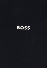 Juodas medvilnės marškinėlis su balta logo, kurioje užrašyta "BOSS" ryškiai, be serifo šriftu, centruota priekyje.