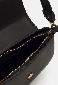 Svart läder axelväska med guldfärgad hårdvara, dragkedjefack och ett insida med kortfack. Slät textur och minimalistisk design.