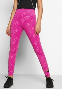 Leggings sportivi rosa con una vita alta e un motivo ripetuto "AIR". Il tessuto è liscio con una leggera lucentezza. Tra gli accenti ci sono aperture alla caviglia.