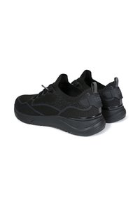Schwarze Sportschuhe mit einem strukturierten Strickobermaterial, einer dick gepolsterten Sohle, elastischen Schnürsenkeln und einer Zuglasche hinten. Verfügt über dezente Branding-Akzente.