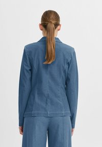 Denimblazer i ljusblått, med skräddarsydd passform, skarpa slag och subtila sömdetaljer, med en mjuk textur och långa ärmar.