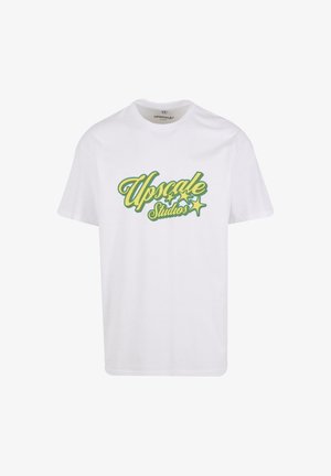 Biely bavlnený tričko s multikolórovým logom "Upscale Studios" so zelenými a žltými akcentami a hviezdnými motívmi. Krátke rukávy, okrúhly výstrih.