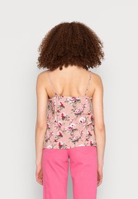 Květinová tílko z růžové látky s nastavitelnými ramínky, zdobené květinovým vzorem v červené a zelené barvě, s volným střihem a hladkou texturou.