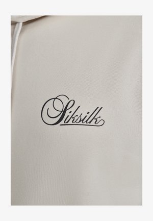 Kremasti dukserica s kapuljačom koja ima crni izvezeni logo "Siksilk" sa stiliziranim natpisom na prednjem dijelu. Mekana, teksturirana tkanina.