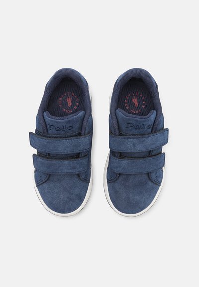 Baskets en daim bleu avec des straps Velcro, semelles en caoutchouc blanc et doublure en tissu texturé. Présentent un logo "Polo" sur la languette.