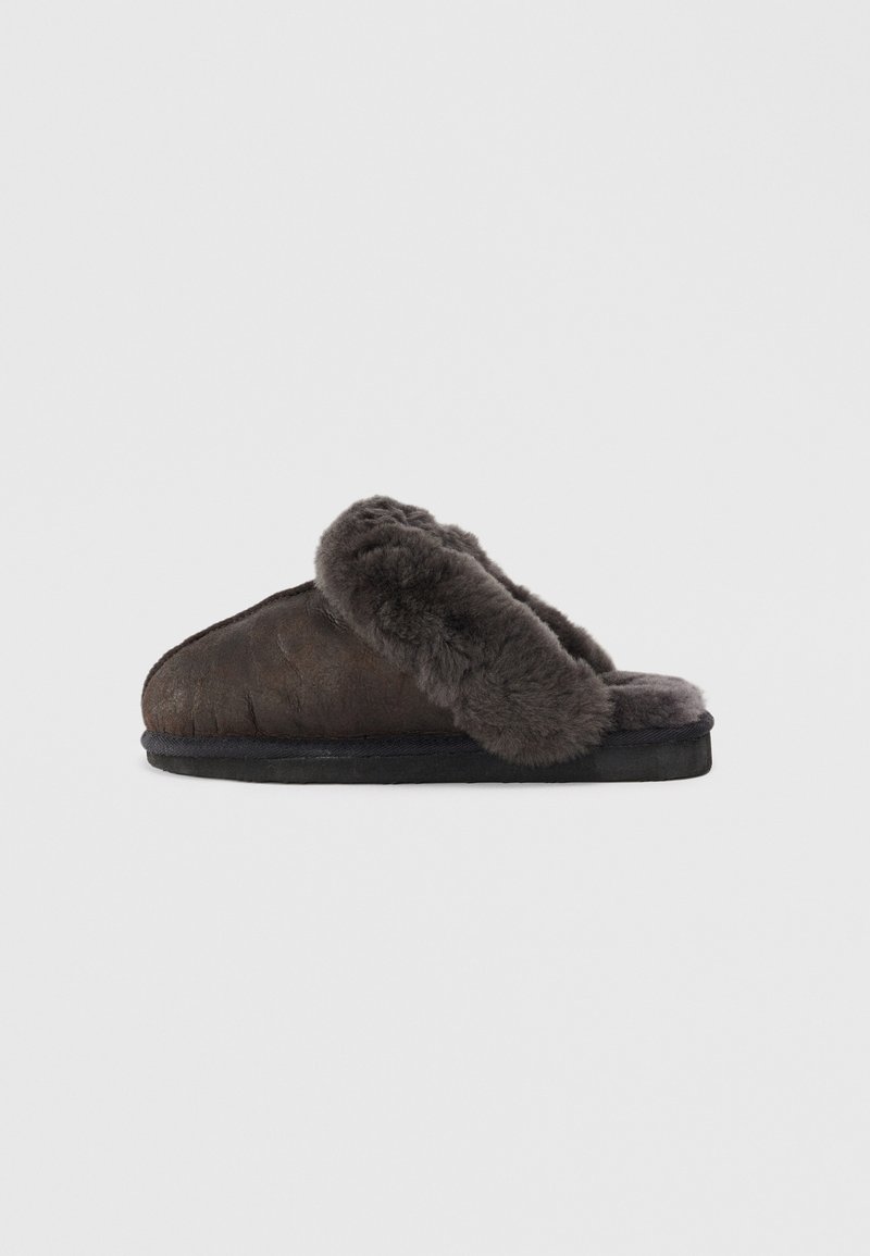 Brown fur-lined slippers with a curved shape, textured leather upper, and a solid black sole. Soft material is prominent around the opening.