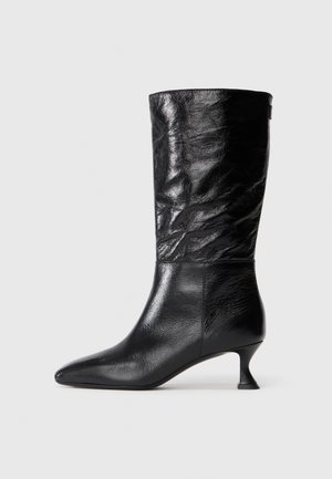 Black mid-calf leather boot with pointed toe, wrinkled upper texture, and low curved kitten heel on a plain white background.