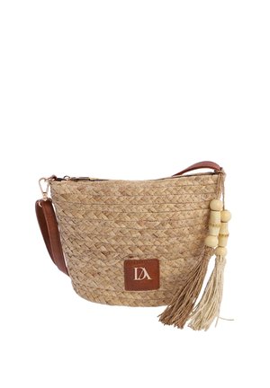 Bolso bandolera de paja trenzada con correa de cuero, parche de logo marrón y dos borlas con cuentas de madera colgando a un lado.