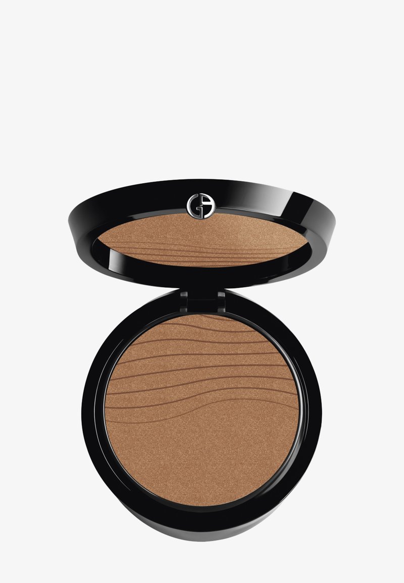 Rund bronzepudderkompakt med en glansfull svart finish. Har en teksturert brun pudderoverflate med bølgemønstre. Sølvlogo på toppen.