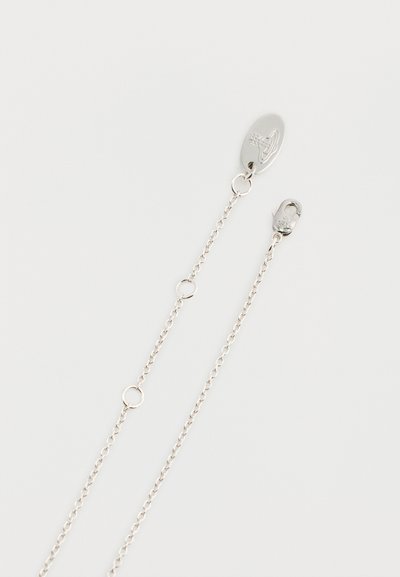 Srebrna verižica z ovalno zaponko, povezovalnimi členki in okroglimi dodatki. Gladek zaključek in nežna zasnova z nastavljivo dolžino.