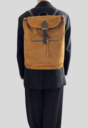 Zaino in suede marrone con design a roll-top, dettagli in pelle, spallacci regolabili e tasca con zip sulla parte anteriore.