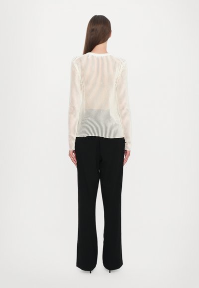 Lightweight, sheer long-sleeve top with vertical white and peach stripes, paired with black tailored pants, visible seams and ventilation.