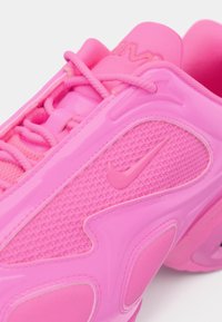 Bright pink Nike sneaker with textured mesh, synthetic overlays, laces, and Nike swoosh logo on the side.