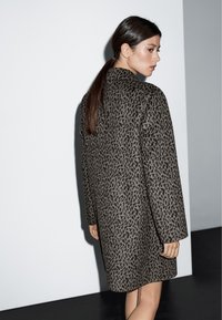 Cappotto in stampa leopardata grigio e nero, di lunghezza media con taglio dritto, maniche lunghe e colletto alto. Texture del tessuto morbida.